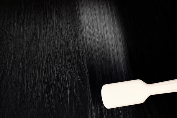 Close-up of the KD680 hair straightening brush beside smooth black hair texture