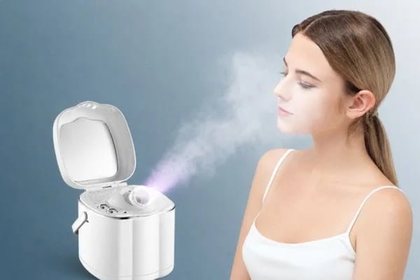 Woman using a facial steamer with open lid and visible warm mist