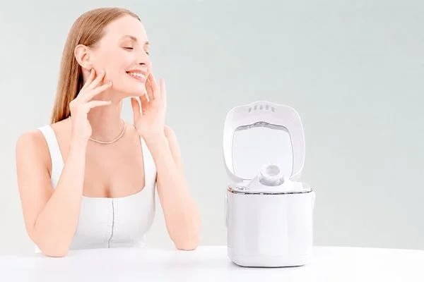 Woman using the KD2332 facial steamer with visible warm mist