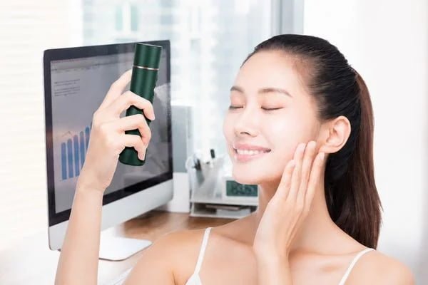 Woman using the KD88SA portable facial mist sprayer in an office setting