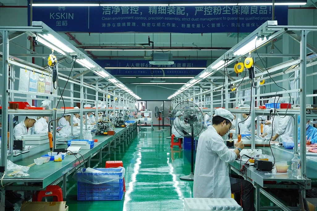 Beauty device assembly workstations along a factory production aisle